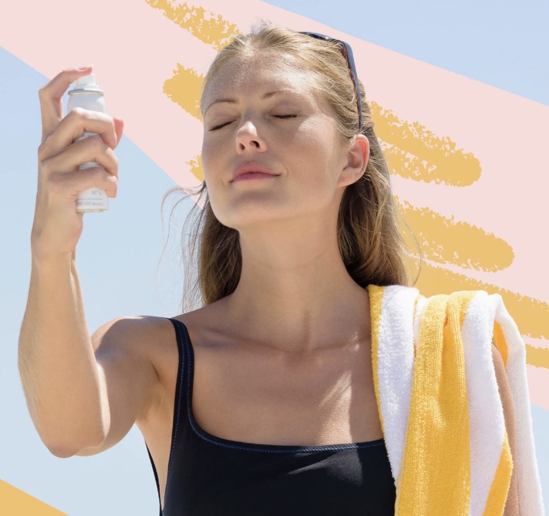 Lady spraying SPF on her face for sun protection in Summer